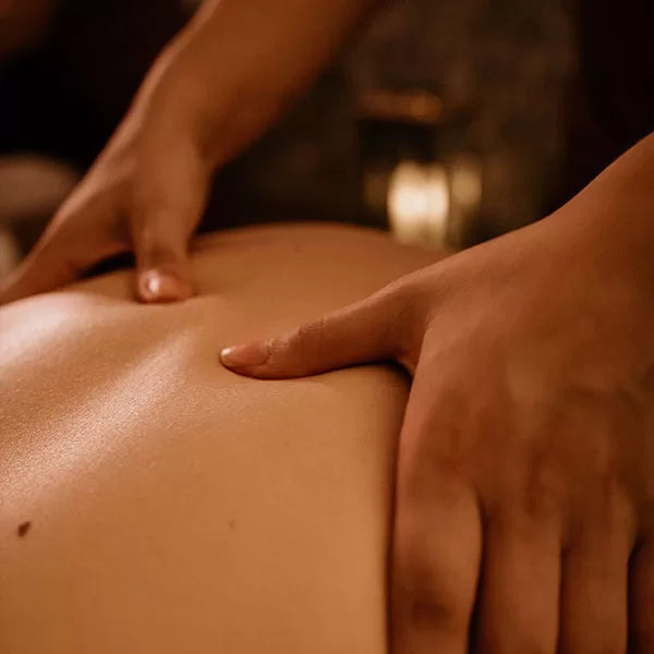 Como parte do produto day spa celebrate a foto mostra as costas de uma pessoa sendo massageada por duas mão, que pressiona os polegares no meio das costas