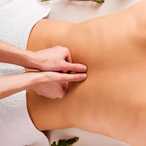 Como parte da experiência massagem áreas de tensão a foto mostra as costas de uma pessoa com uma toalha branca cobrindo seu quadril. duas mão apoiam os polegres na linha da coluna