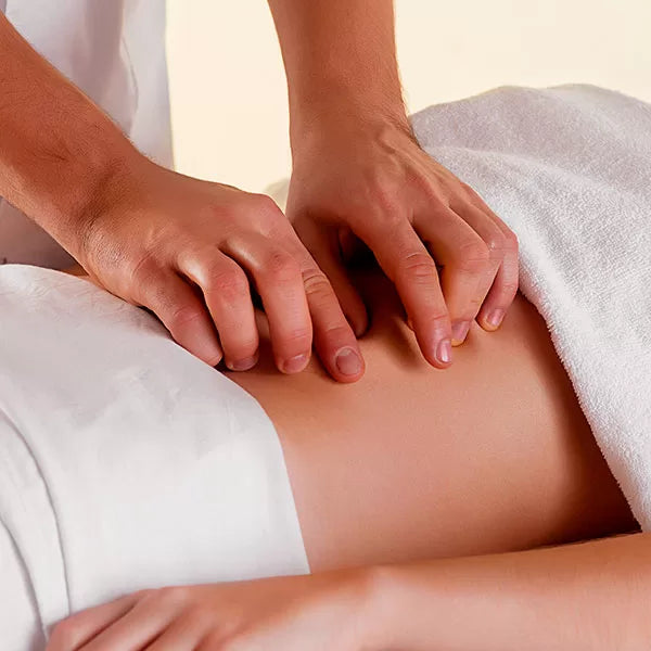 Como parte da experiência massagem áreas de tensão a foto mostra a lateral da barriga de uma pessoa. Uma toalha branca cobre o quadril e outra o peito. Dias mãos ressionam os poleares na barriga