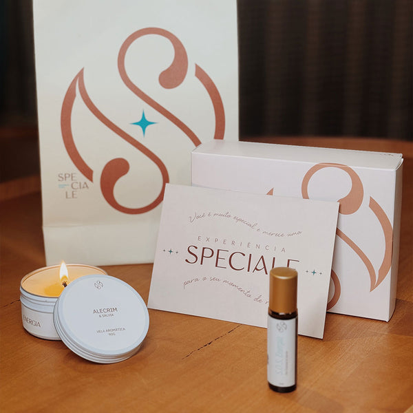 Duas embalagens de papel com o logo da speciale spa estoposicionadas de pé. a frente delas, um cartão com o nome "speciale" também está posicionado de pé, assim como uma pequena embalagem de vidro cilindrica com uma tampa dourada também cilindrica.Ao lado, um recipiente de lata branco está aberto com uma vela acesa e sua tampa também branca e de lata está parcialmente encostadana embalagem