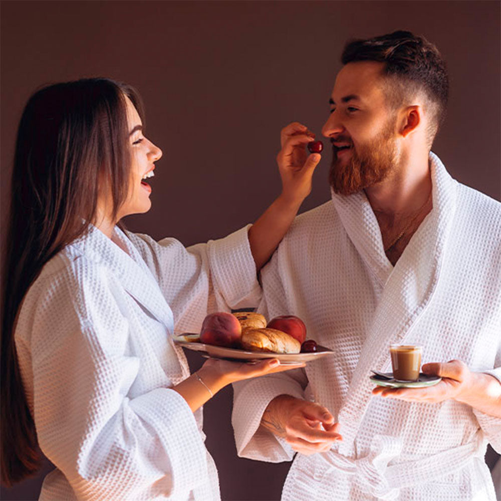 Capa do produto day spa casal no speciale spa representado porum homem e uma mulher, cada um deitado em uma maca, vestindo roupões brancos e recebendo massagem na cabeça. O homem está ao fundo da foto, desfocado, enquanto a mulher está em primeiro plano