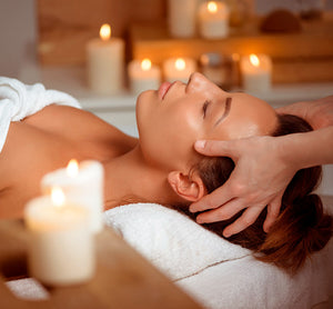 Como parte da experiência do Day Spa Encontro para amigas a foto mostra uma mulher deitada em uma baca, coberta com uma toalha branca, recebendo uma massagem na cabeça