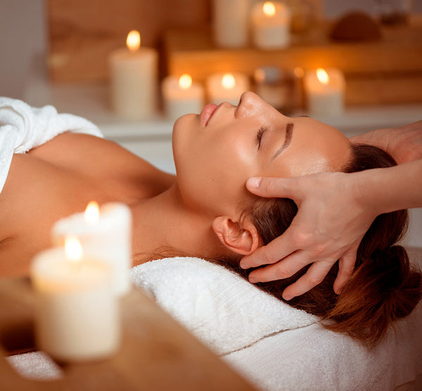 Como parte da experiência do Day Spa Encontro para amigas a foto mostra uma mulher deitada em uma baca, coberta com uma toalha branca, recebendo uma massagem na cabeça
