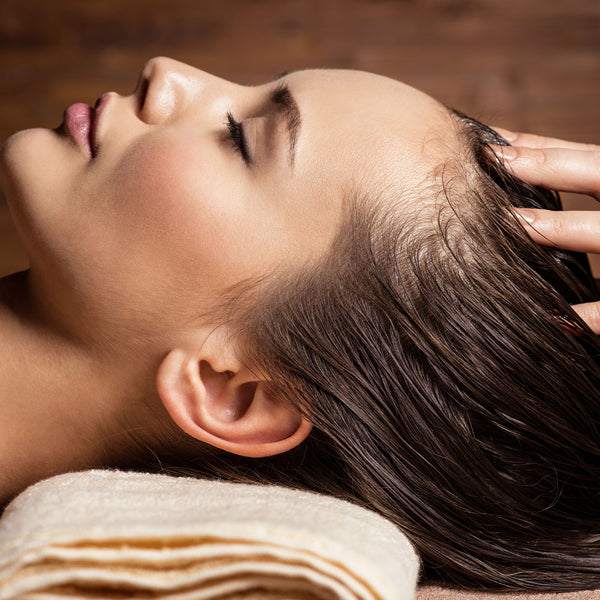 Como parte da experiência do Day Spa lavanda a foto mostra a lateral esquerda do rosto e cabeça de ma mulher deitada e apoiada e uma toalha clara. Seus cabelos estão repousados para trás e as pontas de dedos estão apoiadas em sua cabeça