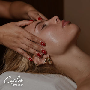 Capa do produto Ciclo Florescer. O ado direito do rosto de uma mulher que está deitada de olhos fechados. Duas mãos estão sobre seu rosto, com os polegares precionando a part4e central de sua testa
